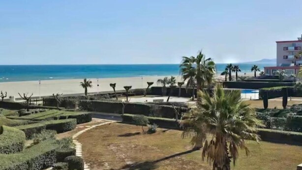 Een kusthotel met uitzicht op het strand, verzorgde tuinen en een zwembad.