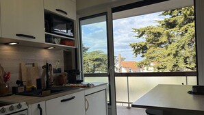 Cozinha com armários brancos, micro-ondas e vista para árvores e edifícios.