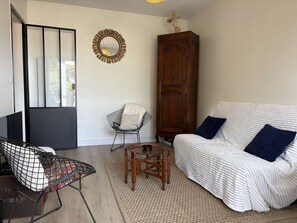 Un salon comprenant un canapé, un fauteuil, un meuble en bois, un miroir et une petite table.