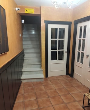 Eine Treppe führt zu einer Zwischenebene mit einer Tür und einem Schild darüber.