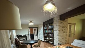 Una sala de estar acogedora con piso de madera, una mesa de comedor, sillas, una estantería y una chimenea.