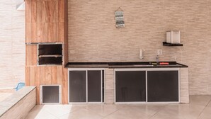Una cocina moderna con armarios de madera, horno empotrado, lavamanos y un letrero colgante.