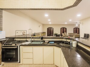 Una cocina moderna con horno integrado, un lavamanos y una zona de comedor con sofá y sillas.