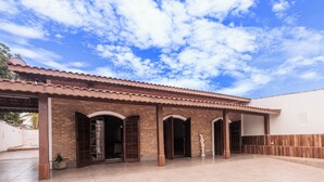 Un patio techado con suelo de baldosas, paredes de ladrillo y puertas de madera.