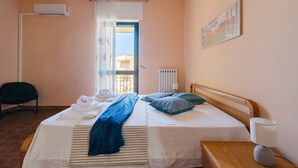 Ein Hotelzimmer mit Bett, Sessel, Heizkörper und einem Vorhangfenster.