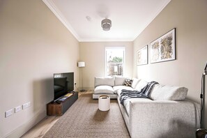 Een woonkamer met een flatscreen televisie, bank en een raam met uitzicht.