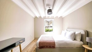 Un dormitorio con cama, escritorio, ventana y lámpara en el techo.