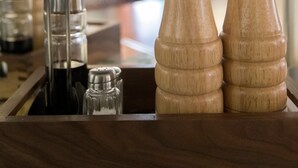 En træbar med salt- og peberkværke, et glas og en metal krog.