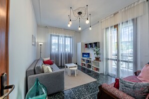 A modern living room with a sofa, a coffee table, a bookshelf, and a TV. - [Dual Suite] Beaches 600m • Cruise Terminal 3km (Savona)