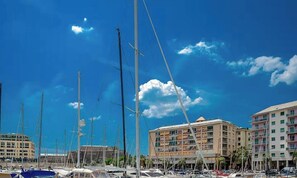 Ein Yachthafen mit mehreren angestuften Booten, ein mehrstöckiges Gebäude mit Balkonen und einem strahlend blauen Himmel.