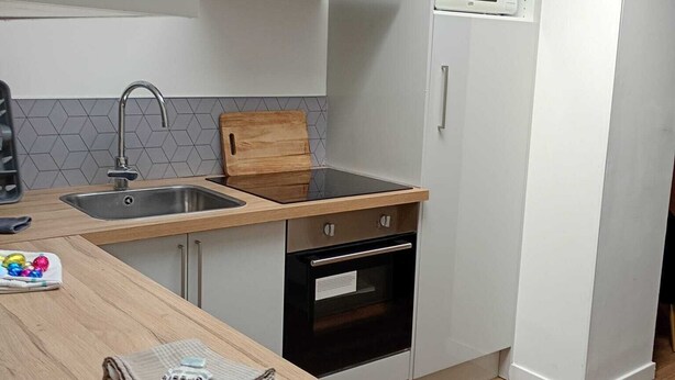 A compact kitchen with a sink, stove, microwave, and wooden countertop.