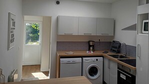 A compact kitchen with a skylight, a washing machine, a coffee maker, and a microwave.