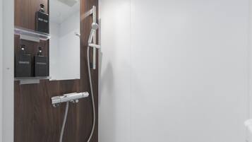 A modern bathroom with a wooden vanity, a mirror, and a shower with a handheld showerhead.