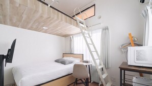 A compact hotel room with a bunk bed, a desk with a chair, a television, and a microwave.