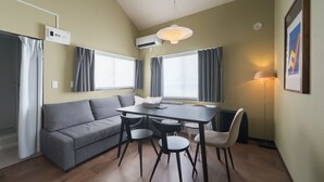 Un salon moderne avec un canapé gris, une table à manger avec des chaises, un luminaire suspendu et un radiateur.