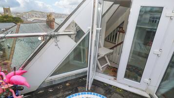 Una habitación con puerta de vidrio, una pequeña mesa blanca y vistas a la ciudad.