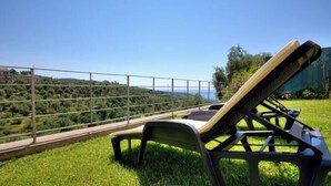 A sun lounger on a grassy lawn with a view of a hilly landscape and a clear sky. - Grace house (CIVEZZA)
