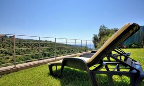 A sun lounger on a grassy lawn with a view of a hilly landscape and a clear sky. - Grace house (CIVEZZA)