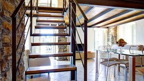A staircase with wooden steps and metal railings, leading to a dining area with a glass table and chairs. - Grace house (CIVEZZA)