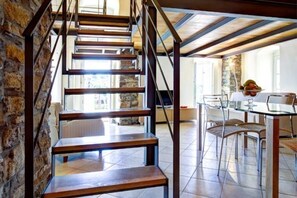 A staircase with wooden steps and metal railings, leading to a dining area with a glass table and chairs. - Grace house (CIVEZZA)