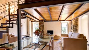A modern interior with a glass dining table, a sofa, a TV, and a stone accent wall. - Grace house (CIVEZZA)