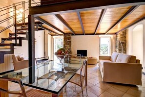 A modern interior with a glass dining table, a sofa, a TV, and a stone accent wall. - Grace house (CIVEZZA)