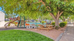A playground with a slide, climbing structures, and a picnic table. - Cozy 2-bedroom apartment in tranquil St. George with AC and gym Southgate (St. George)