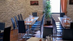 Una sala de conferències amb taules llargues, cadires i una planta en test.