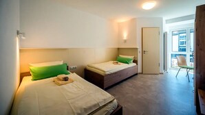 Une chambre d’hôtel avec deux lits, une porte et une vue sur l’extérieur.