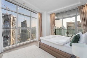 Ein modernes Schlafzimmer mit großem Fenster, einem Bett und Blick auf die Stadt.