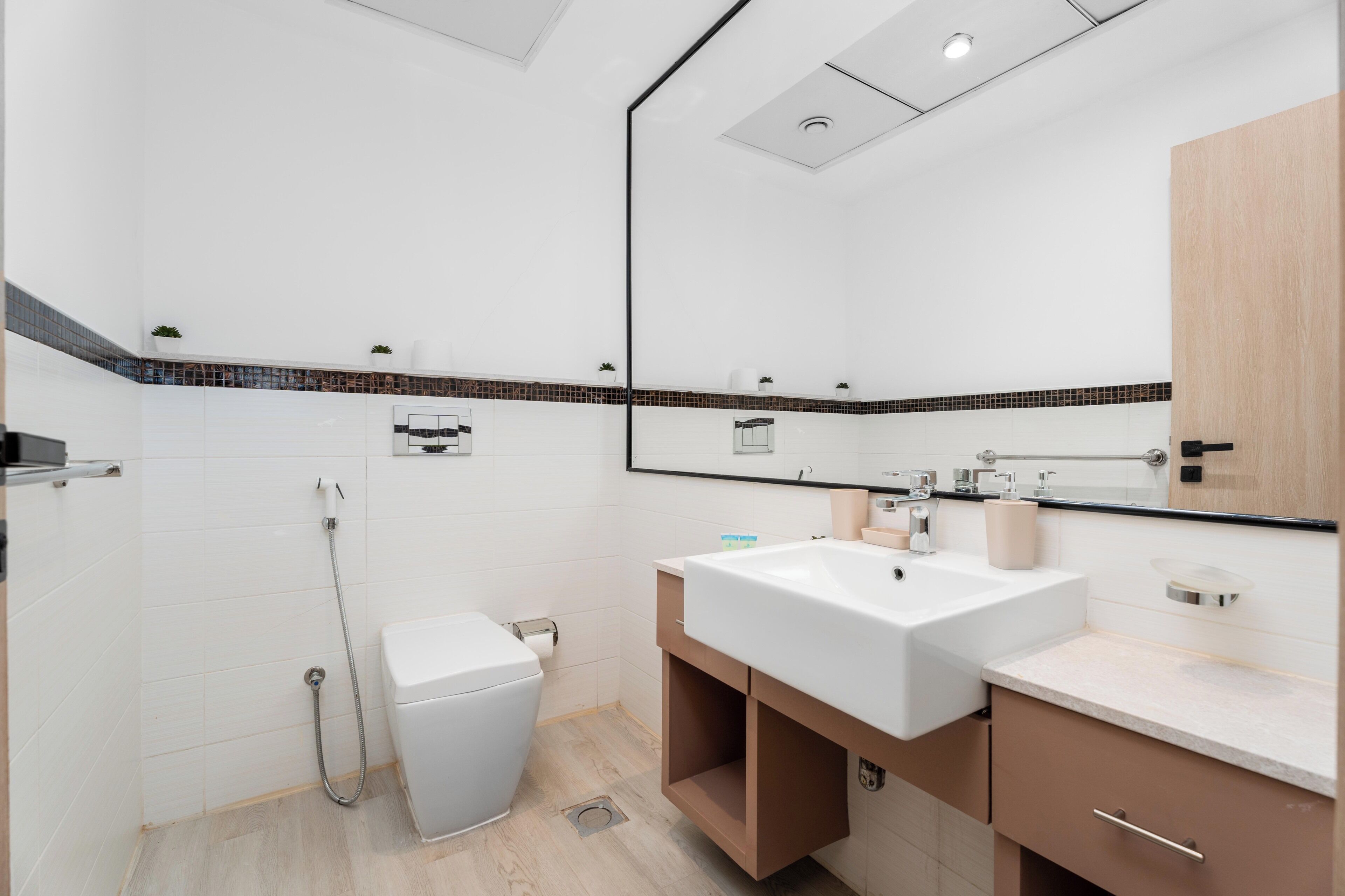 A modern bathroom with a white toilet, a sink, a mirror, and a shower.