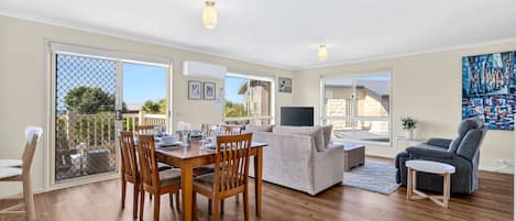 A spacious living area with a dining table, sofas, and a TV.