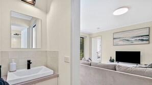 Un bany modern amb un mirall gran, un lavabo blanc i una zona de dutxa.