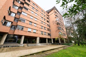 A multi-story brick building with a flat roof, large windows, and a central courtyard with steps leading to a covered area. - M (MOS34D7E) Spacious and elegant two-bedroom apartment with terrace (Madrid)