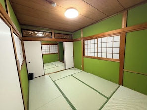 A traditional Japanese room with tatami flooring, sliding doors, and a ceiling light fixture. - Quiet 4BR Home Near KIX | Long Stay Welcome (Izumisano)
