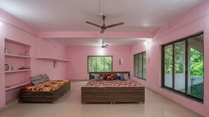 Un dormitorio con decoración rosa, dos camas de madera, un ventilador de techo y ventanas grandes.