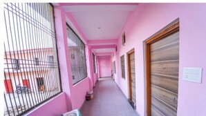 Un pasillo estrecho con paredes rosadas, una reja de metal y una puerta de madera cerrada.