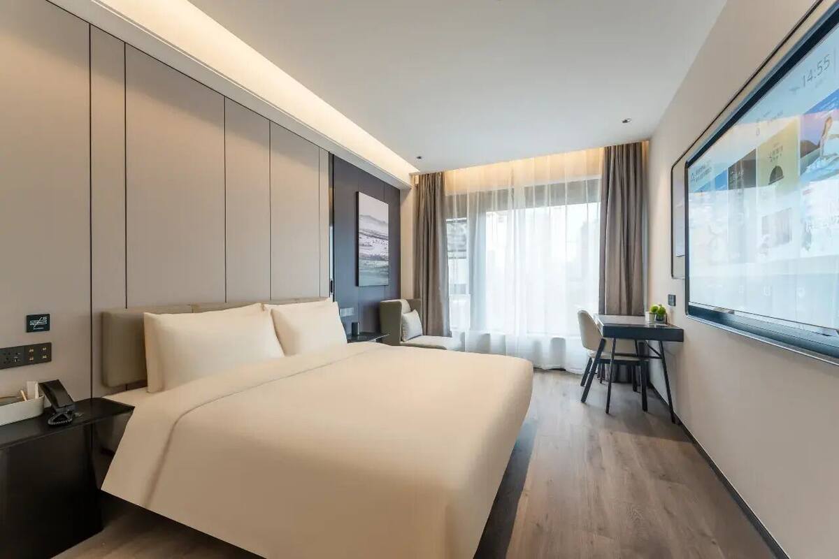 Una habitación de hotel con una cama grande, un escritorio y una ventana.