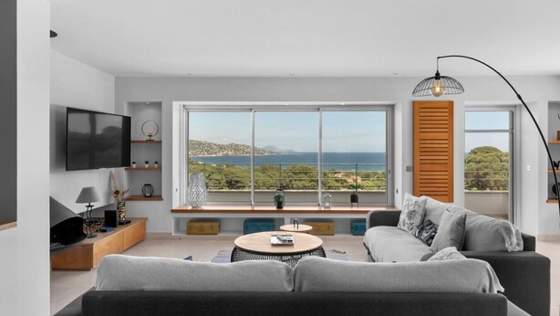 Un salon moderne doté d’une grande fenêtre, d’un téléviseur à écran plat et d’un canapé.