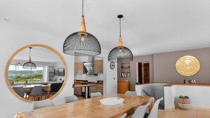 Une cuisine moderne avec vue, un coin repas doté d’une table en bois et une pancarte indiquant « BIENVENUE ».