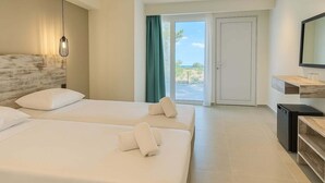 A hotel room with two beds, a TV, a small kitchen area, and a view of the outdoors. - Evita Flamingo (Kos)