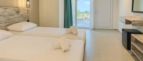 A hotel room with two beds, a TV, a small kitchen area, and a view of the outdoors.