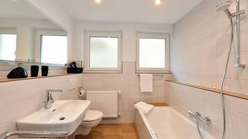 Un baño moderno con lavamanos, inodoro, bañera y ducha.