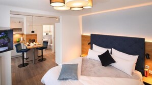 Una habitación de hotel con cama, mesita de noche, lámpara y televisor sobre un mueble.