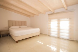 Una camera da letto con un letto, un comodino, una porta scorrevole e un soffitto spiovente.