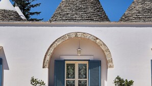 Um edifício com fachada branca, entrada em azulejos e porta azul.