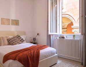 Une chambre à coucher avec un lit, une fenêtre, un radiateur et une vue sur une arche.