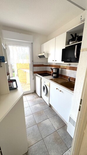 A compact kitchen with a washing machine, a microwave, and a stove. - Apartment "Bord de Mer" 5min beach, pool, AC (Fréjus)