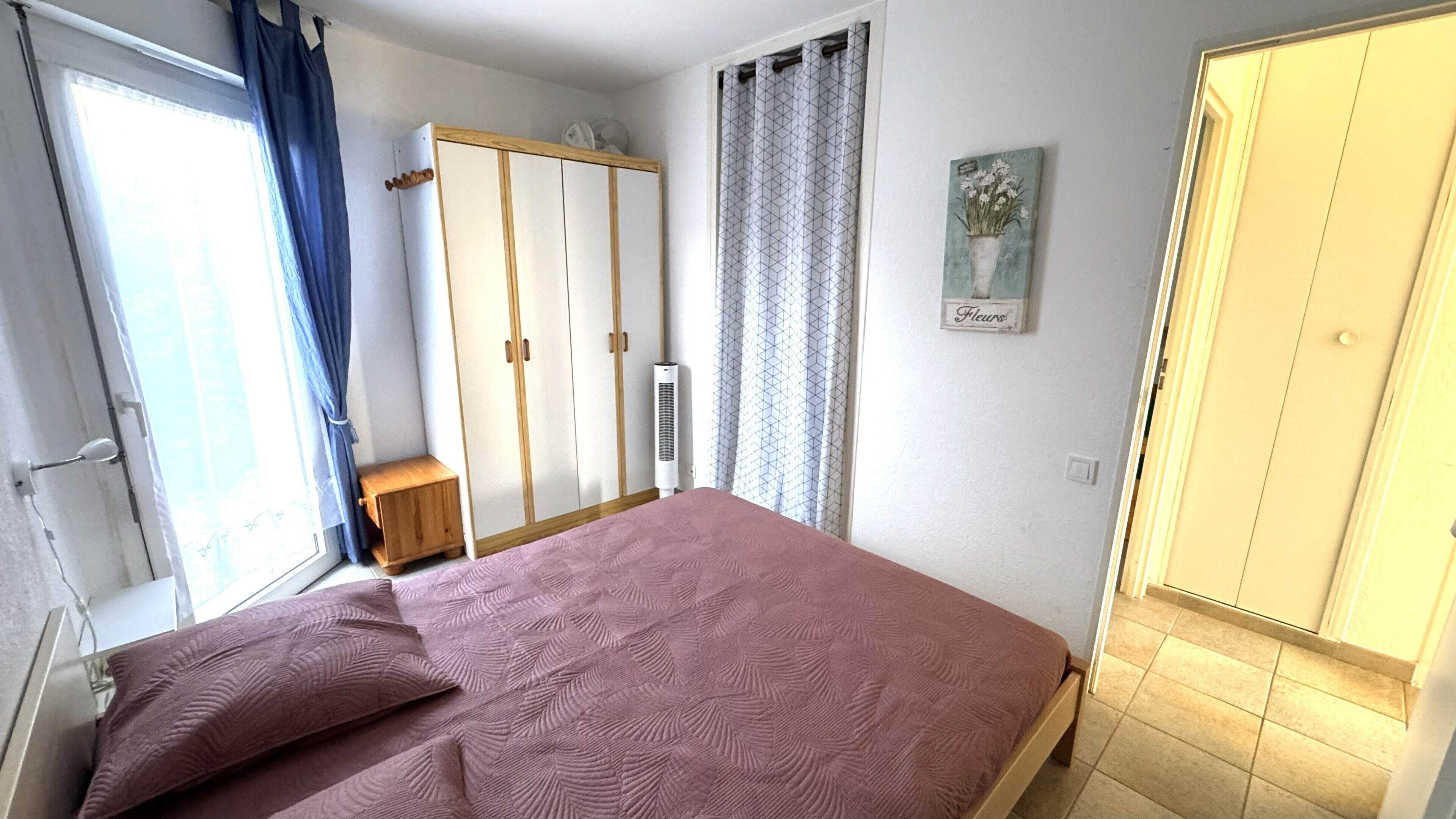 A bedroom with a bed, wardrobe, and a small table.