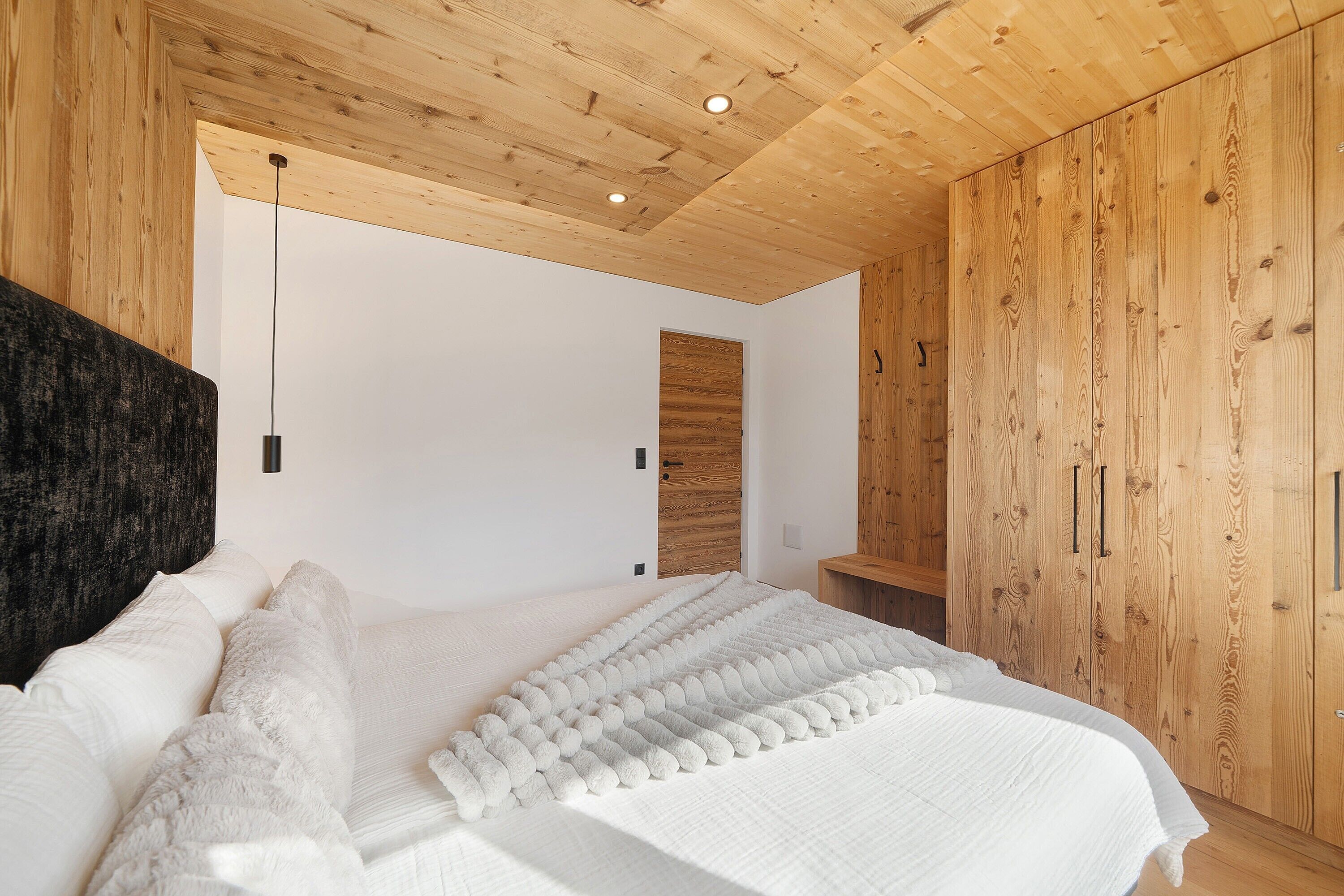 Ein Schlafzimmer mit Holzboden, einem Bett mit weißer Bettwäsche und Holzwänden.